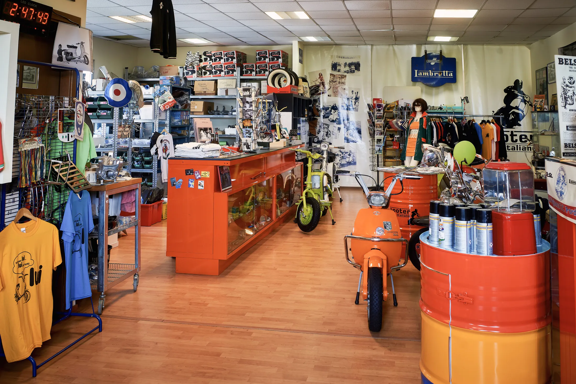 L'interno del negozio Scooter Italiano, con banco arancione, ricambi e abbigliamento